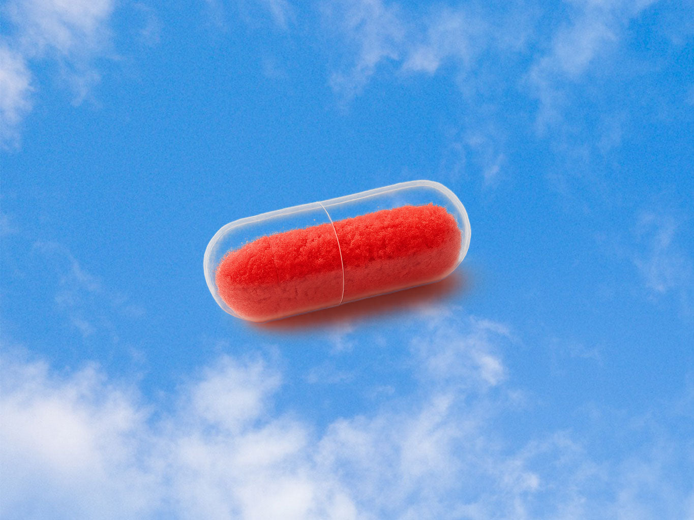 transparent pill capsule bright red powder sky clouds